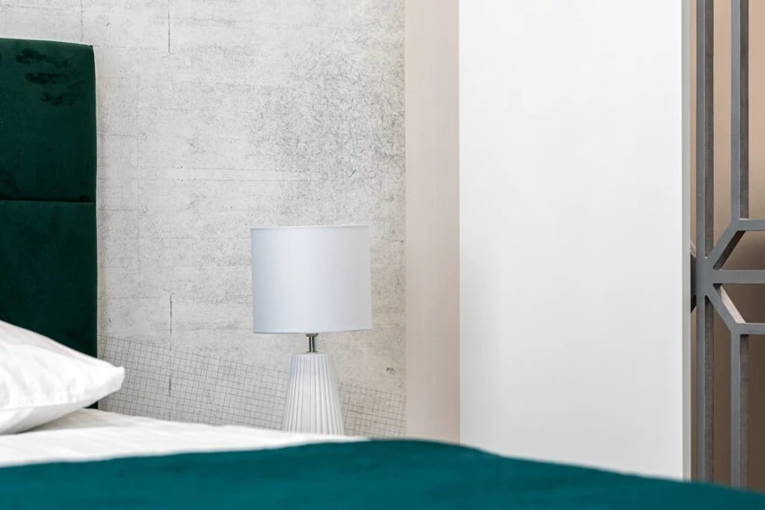 Nocna lampka na stoliku przy łóżku w apartamencie w Toruniu